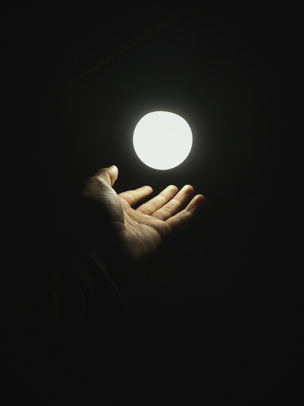 una mano sosteniendo una luz en la oscuridad