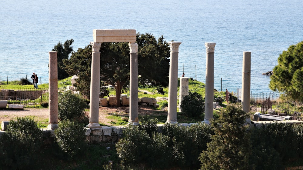 a group of pillars in front of a body of water