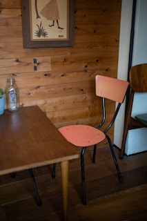 A cozy corner with a framed watercolor artwork hanging above a wooden side table with a small plant.
