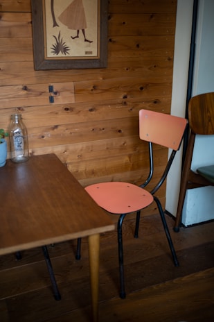A cozy corner with a framed watercolor artwork hanging above a wooden side table with a small plant.