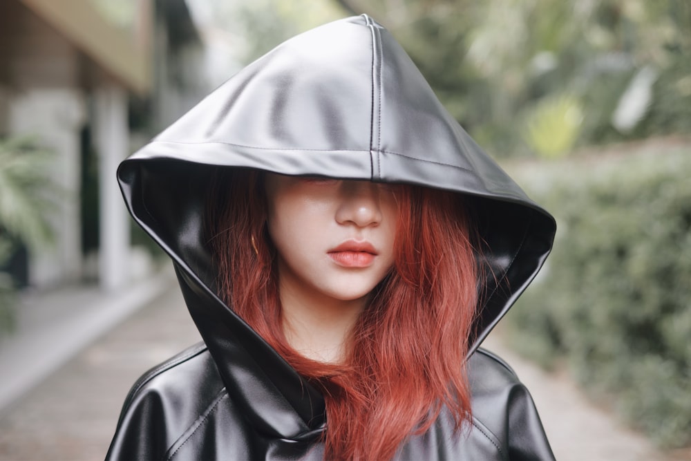 a woman with red hair wearing a black leather hoodie