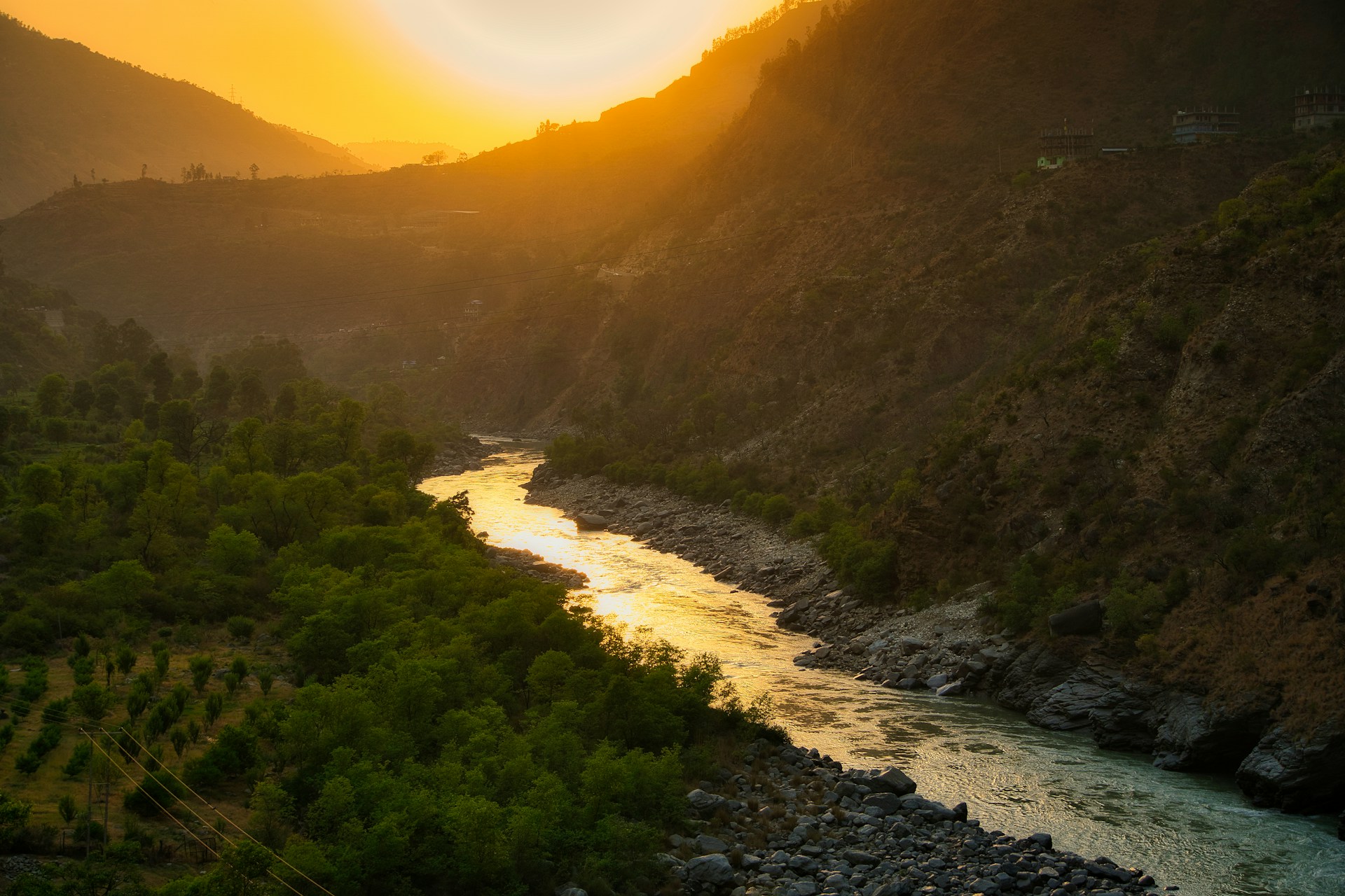 A serene landscape photo with golden hour light illuminating rolling hills and a winding river