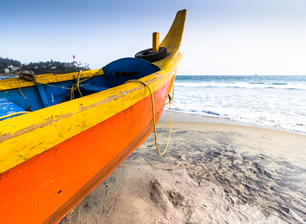 a yellow and blue boat sitting on top of a sandy beach