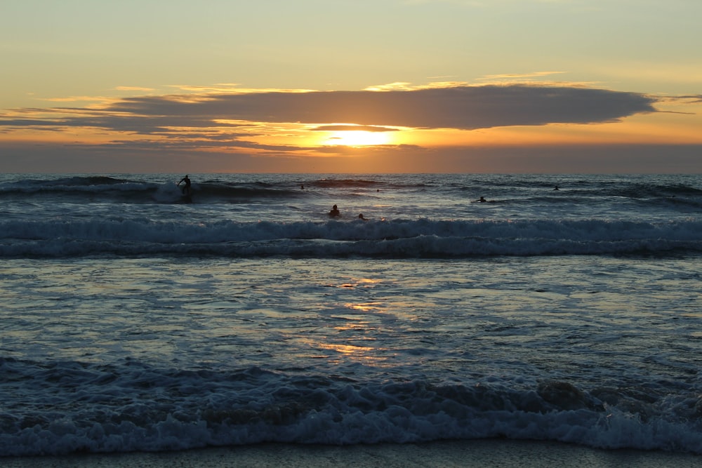 a sunset over the ocean with surfers in the water