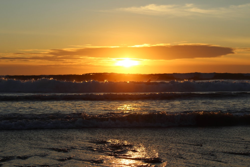 the sun is setting over the ocean waves