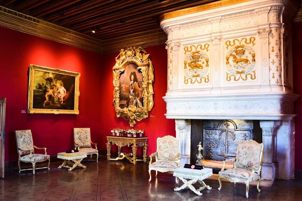 a room with a fireplace, chairs and paintings on the wall