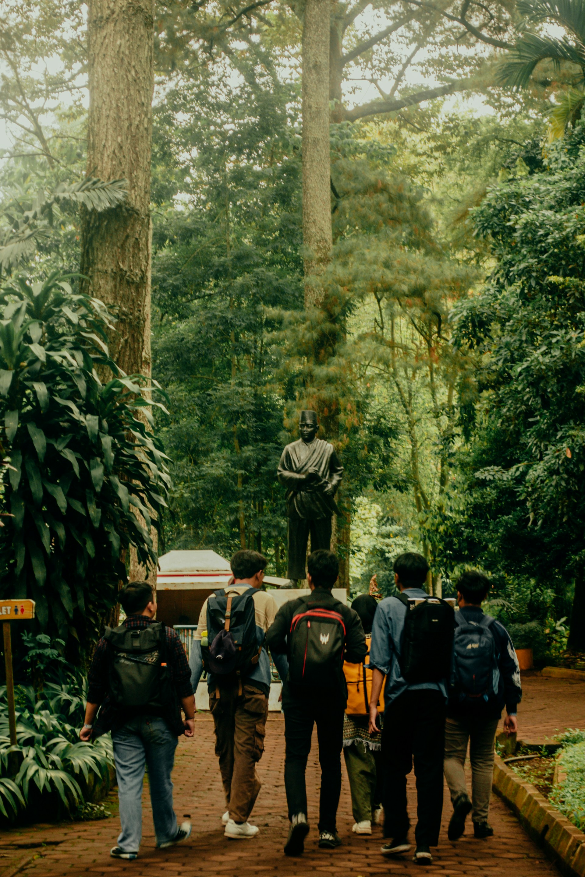 A vibrant group of travelers walking together along a historic pilgrimage trail surrounded by lush greenery.
