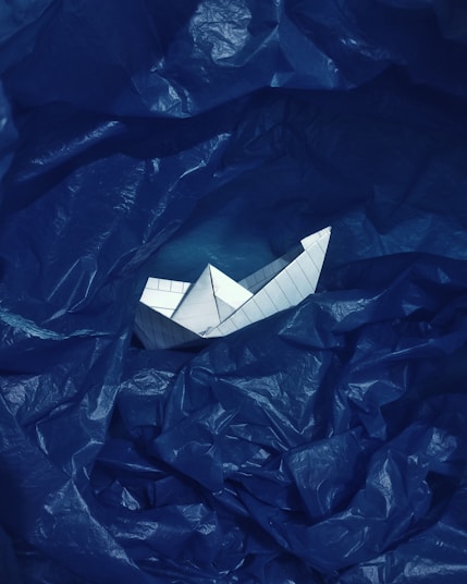 a paper boat floating on top of a blue plastic bag