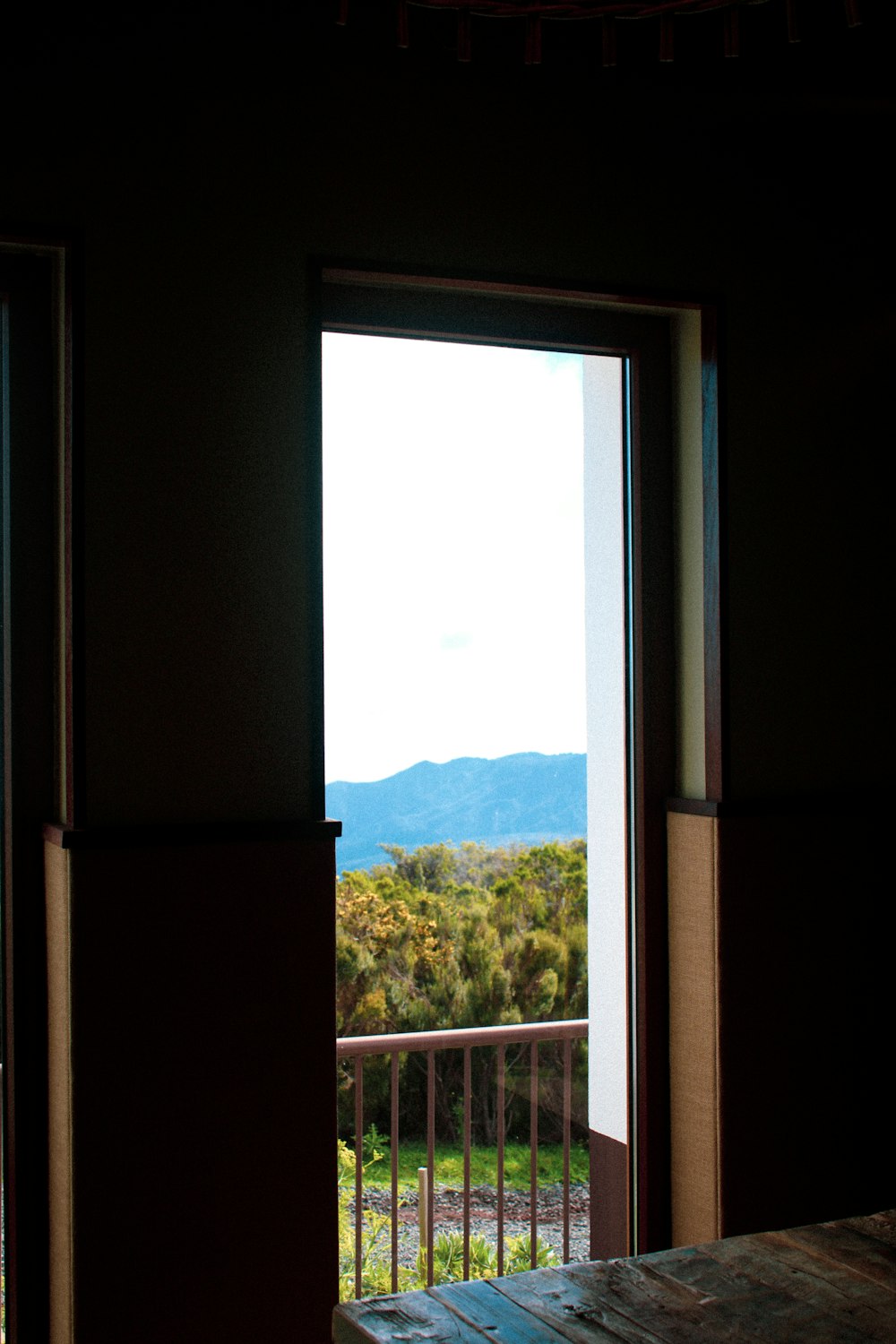 an open door leading to a balcony with mountains in the distance