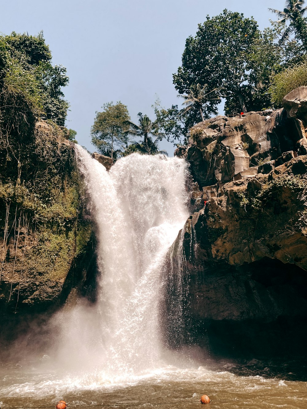 a large waterfall with people swimming in it