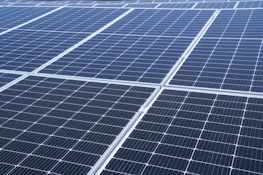 Close-up of solar microinverters connected to photovoltaic panels with sunlight reflecting.
