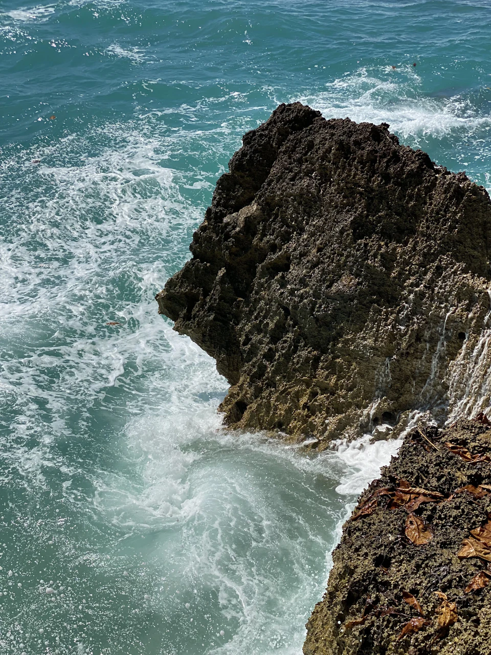 Rocky cliff face features large jagged rock formation on right and smaller smooth one left
