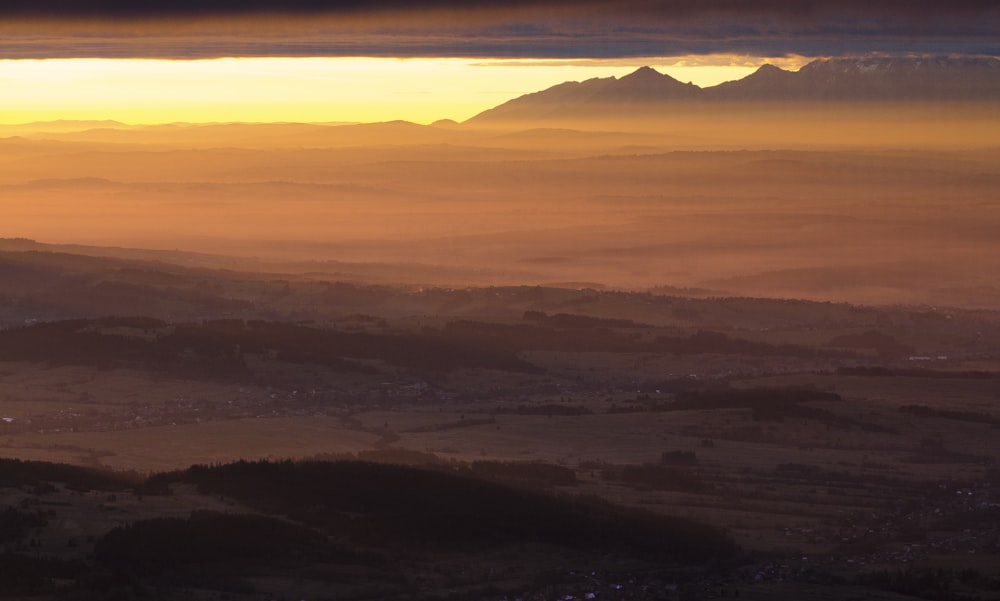 the sun is setting over a valley with mountains in the background