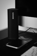 a black and white photo of a cell phone and a speaker