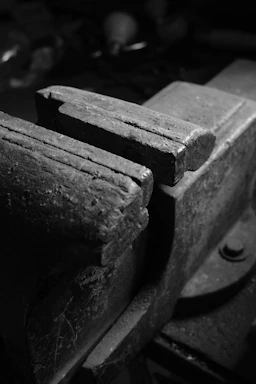 Close-up of industrial metal hinges and clamps arranged on a dark metallic surface.