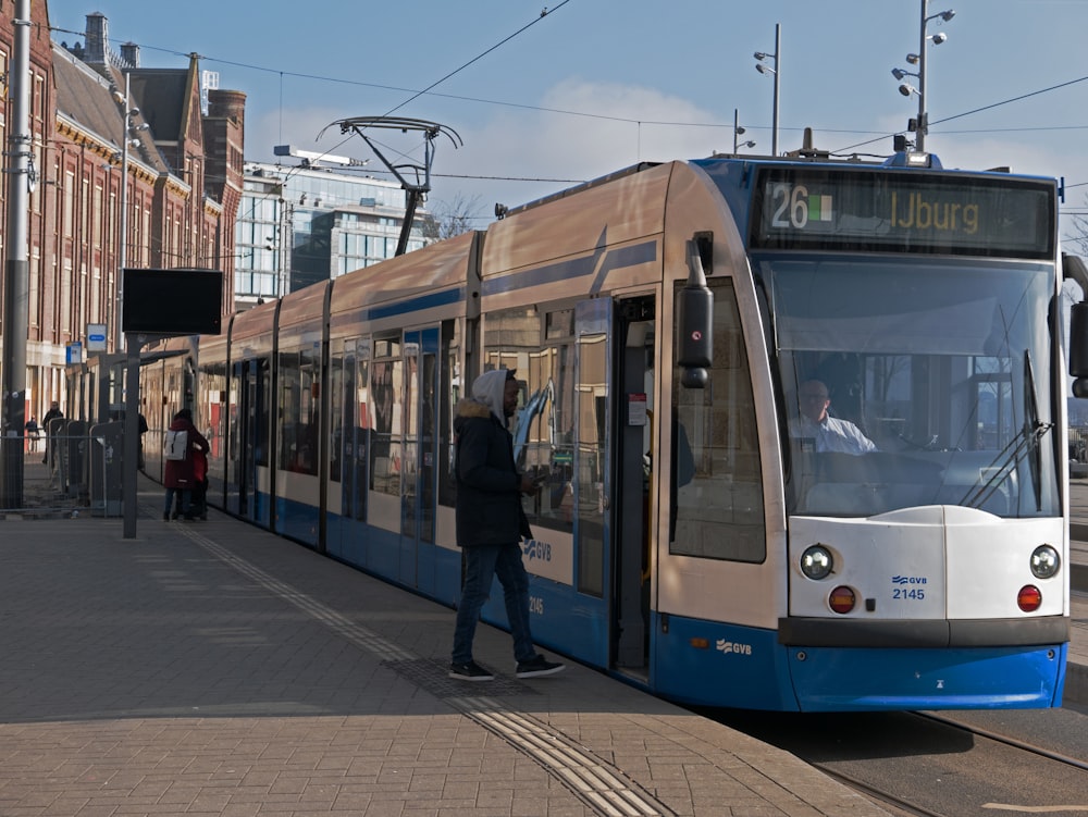 a blue and white train pulling into a train station