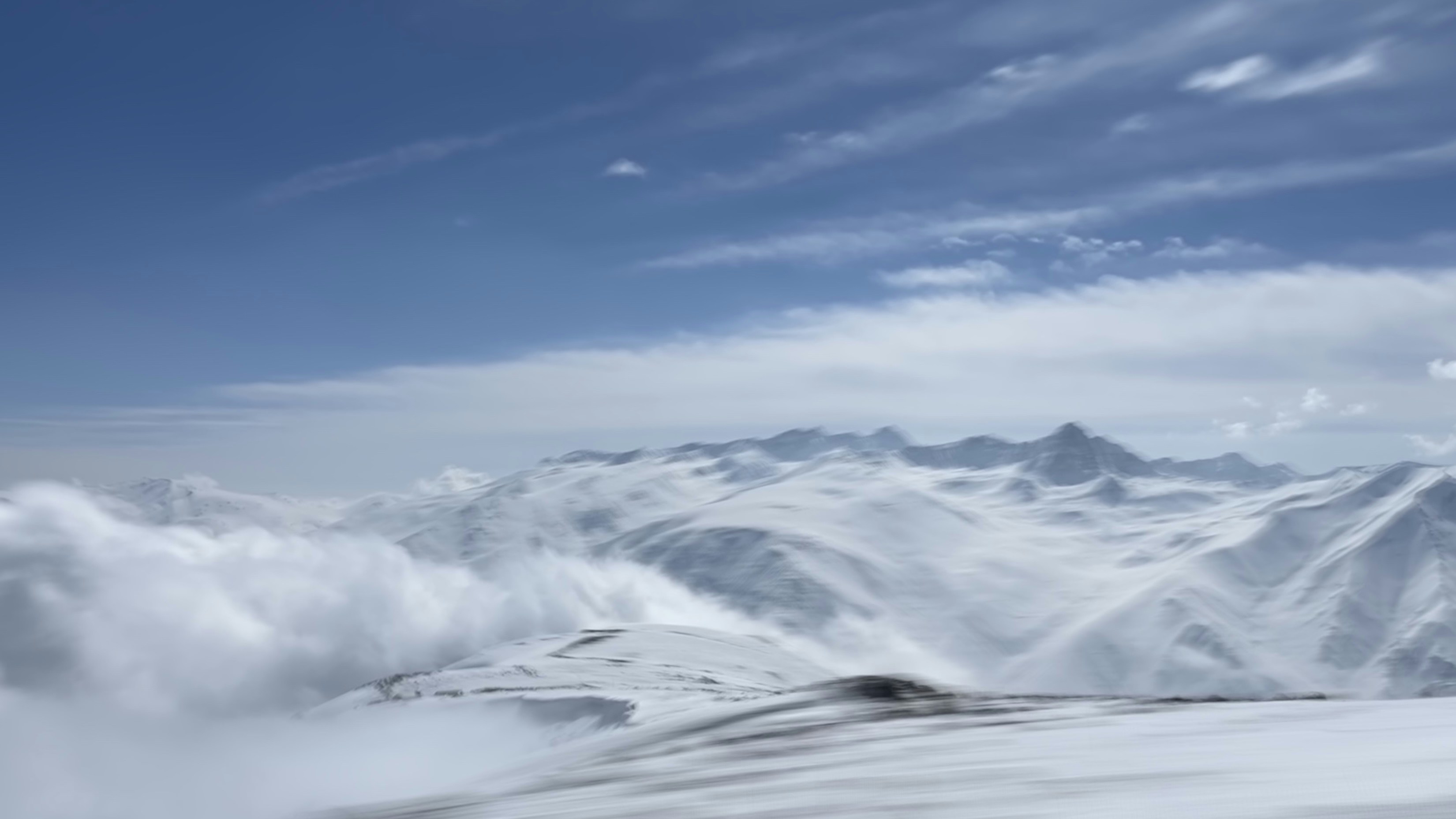 a mountain range covered in snow under a blue sky