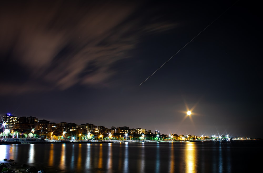 a night view of a city with a plane flying over it