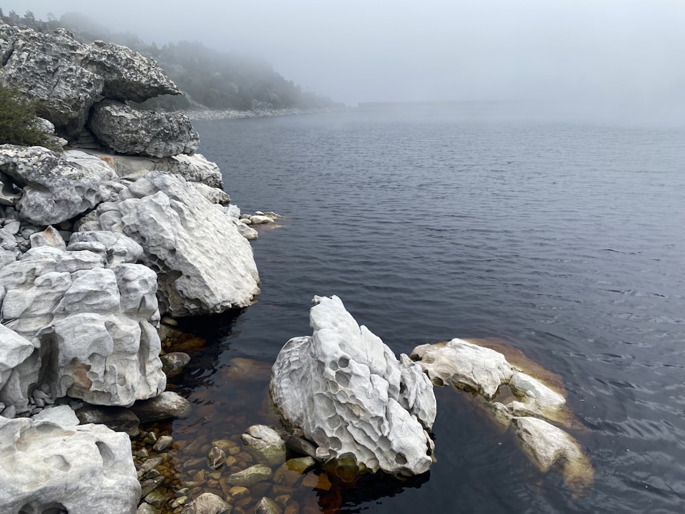 a body of water surrounded by rocks and fog