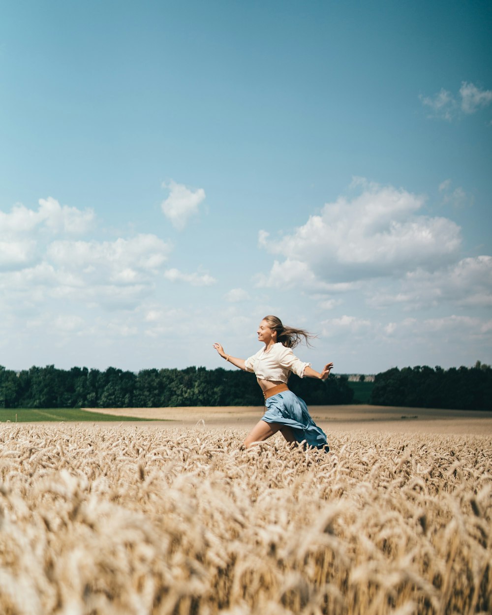 a woman running through a field of wheat