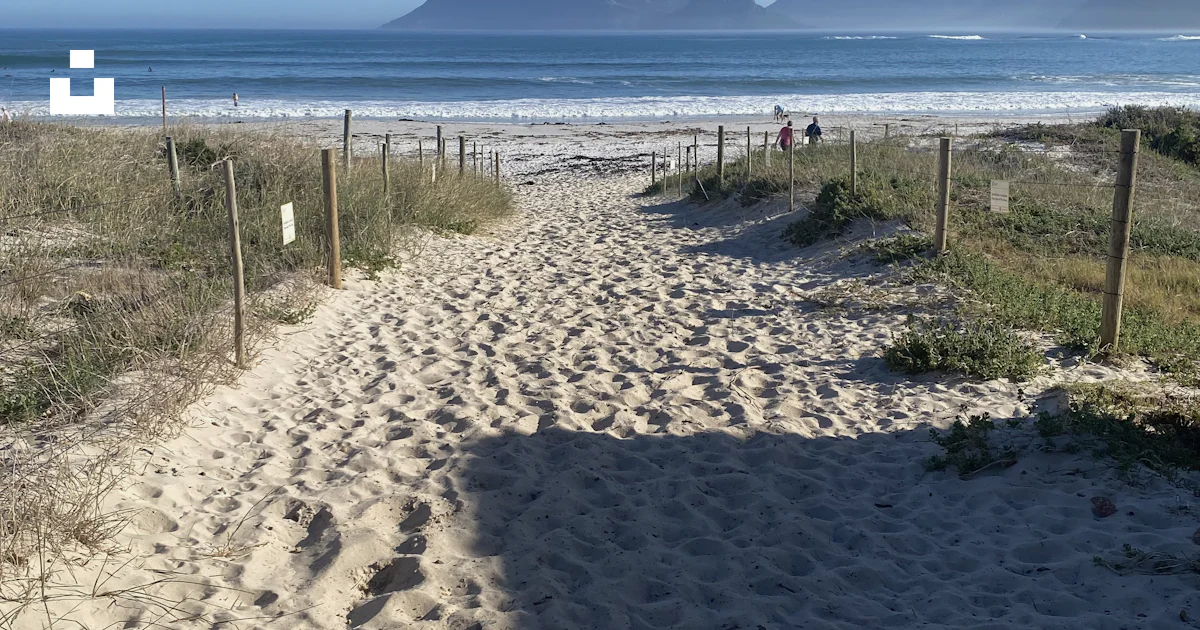 A sandy path leading to the beach with mountains in the background ...