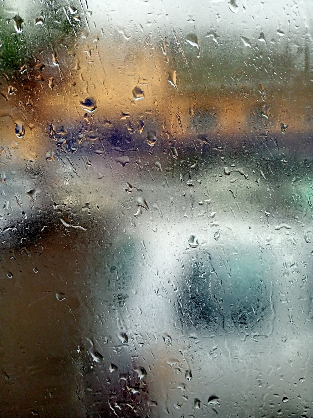 rain drops on a window with cars in the background