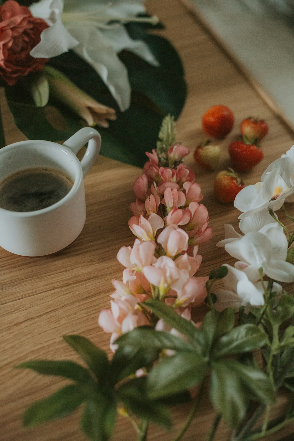 a cup of coffee and some flowers on a table