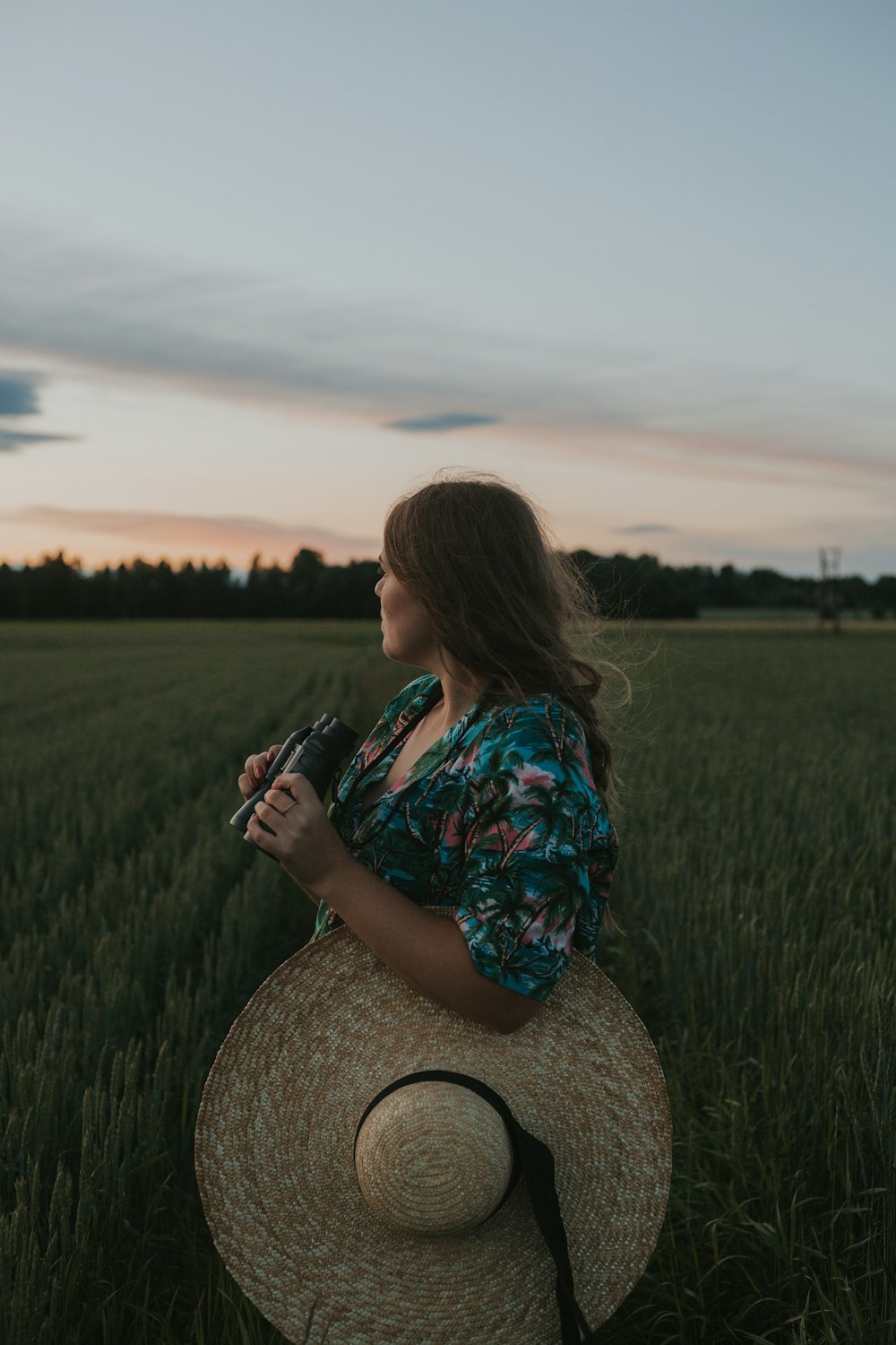 a woman standing in a field holding a camera