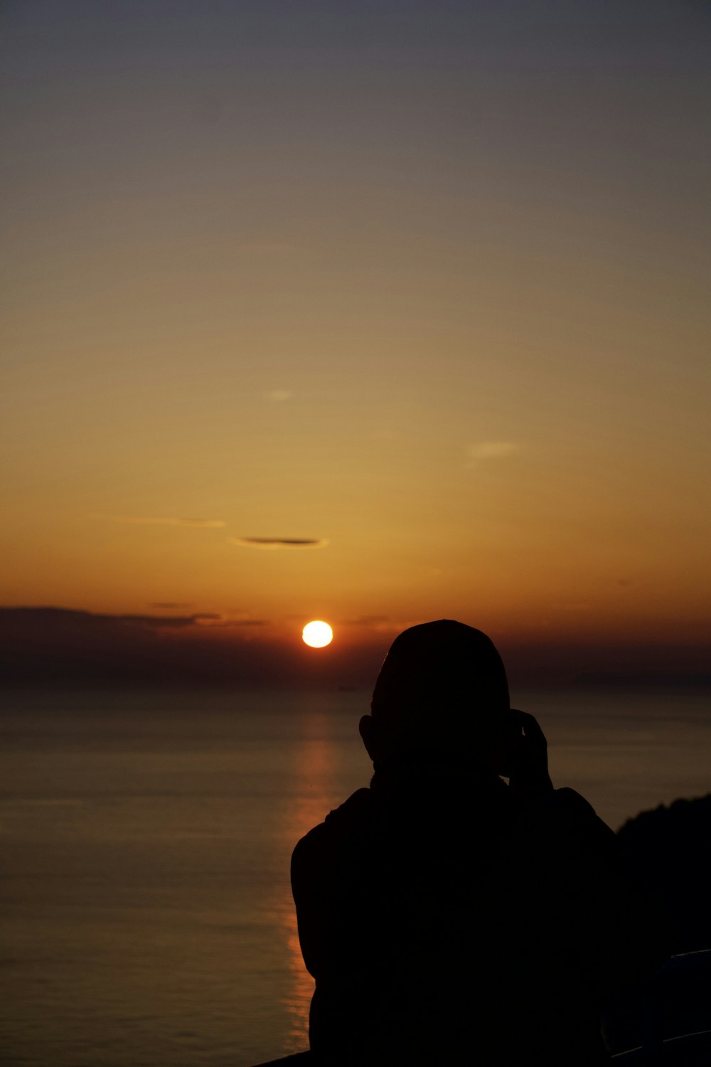 a person sitting on a bench looking at the sunset