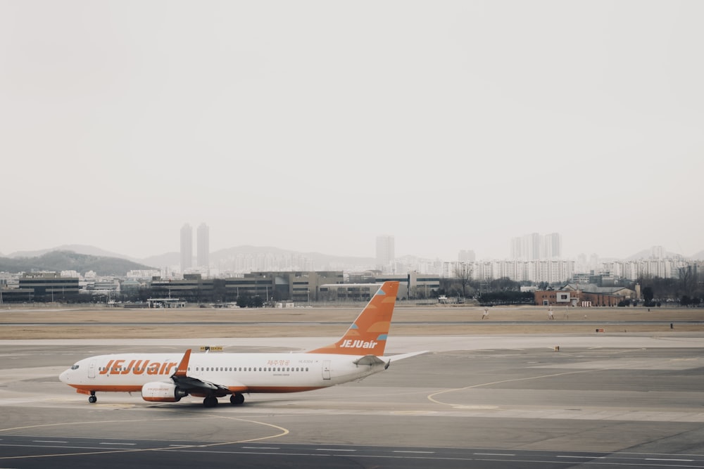 an orange and white airplane is on the runway