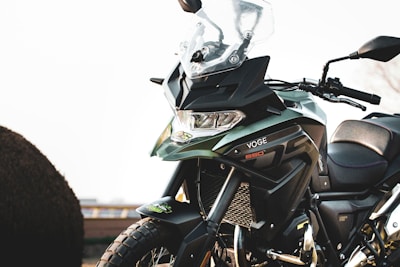 A close-up of a modern motorcycle with a sleek design. The bike features a large windshield, angular headlights, and distinctive branding on the body. Its bodywork includes a combination of metallic and matte finishes.