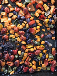A vibrant bowl of colorful roasted vegetables with fresh herbs sprinkled on top.