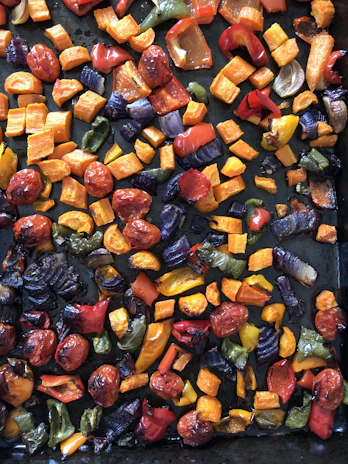 A vibrant bowl of colorful roasted vegetables glistening with herbs and olive oil.