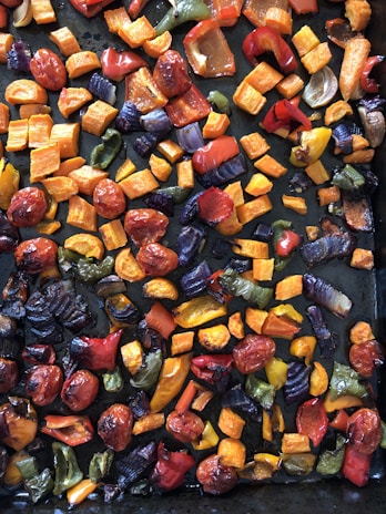 A vibrant bowl of colorful roasted vegetables with fresh herbs sprinkled on top.