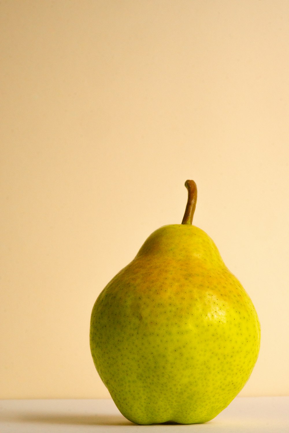a green pear sitting on top of a white table
