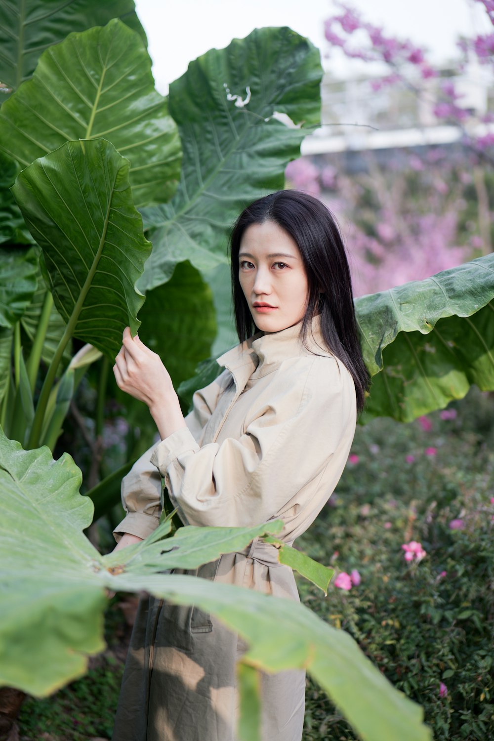 a woman standing in front of a lush green plant