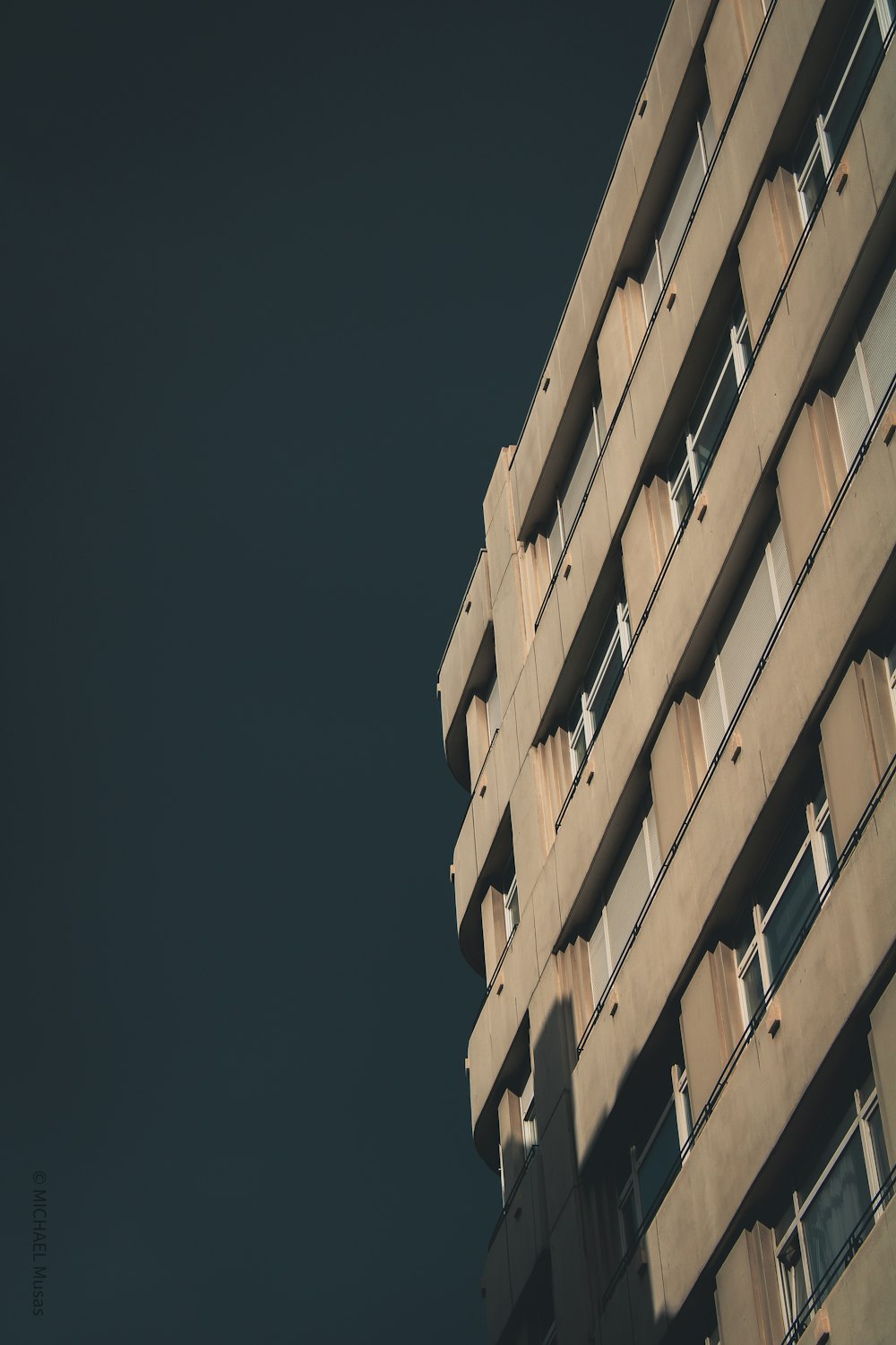 a tall building with balconies against a dark sky