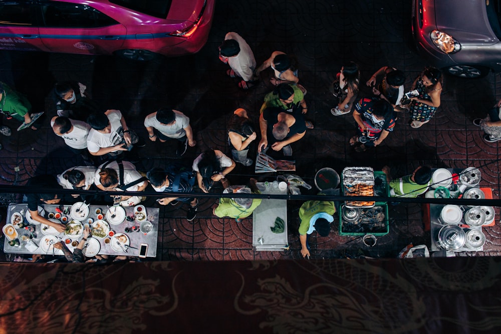 a group of people standing around a table with food