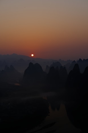 The serene Li River with karst mountains reflecting in the water at sunrise.