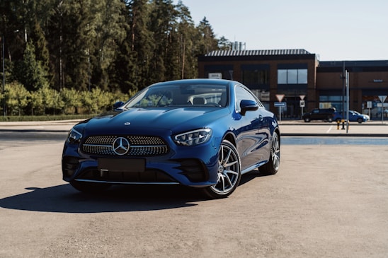 A sleek dark blue car parked in front of the Nogent Auto Premium dealership on a sunny day.