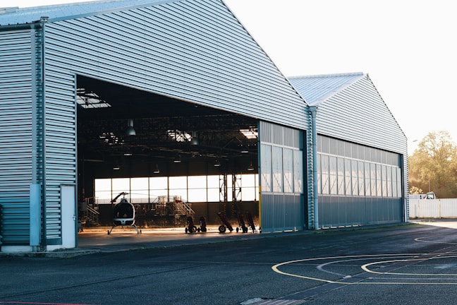 A massive aircraft hangar door smoothly sliding open against a clear blue sky