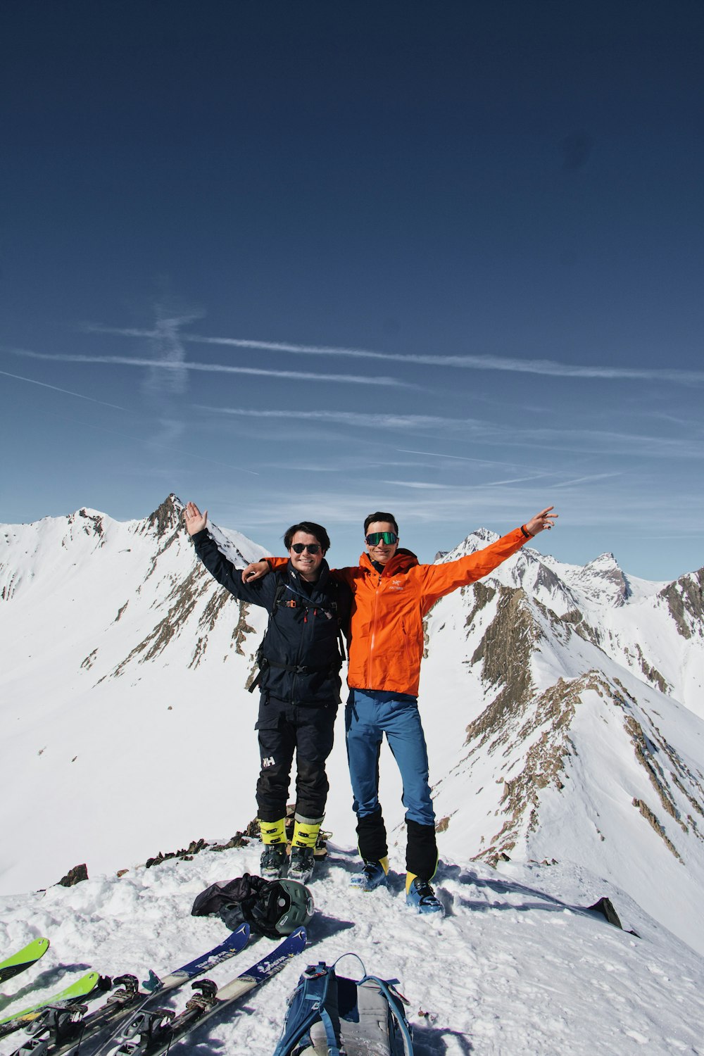 a couple of men standing on top of a snow covered slope