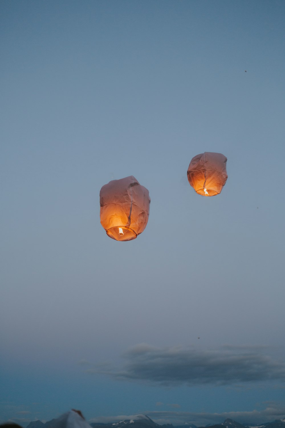 a couple of paper lanterns floating in the sky