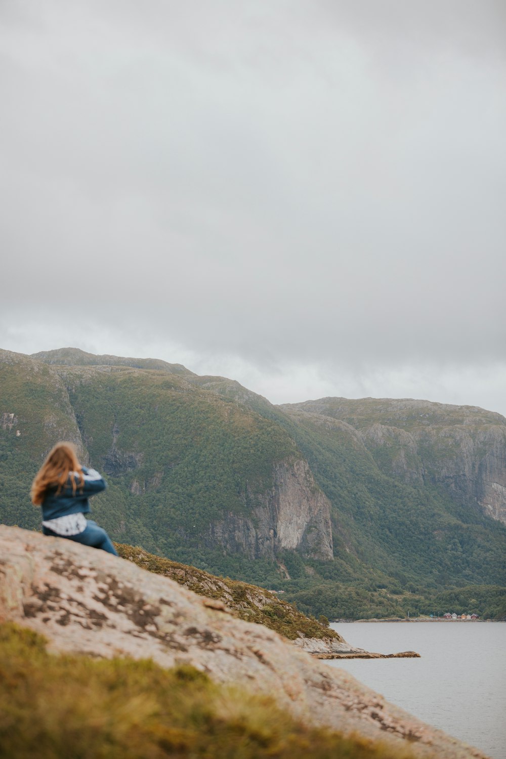 a woman sitting on top of a rock next to a body of water