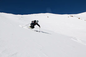 A skier wearing advanced protective gear, including a sensor-equipped helmet, gliding down a snowy slope.