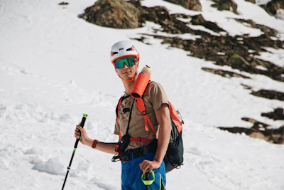 a man with a backpack and skis standing in the snow