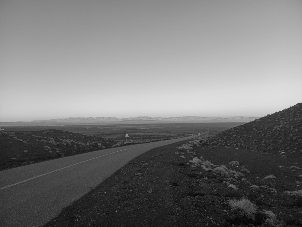 a black and white photo of a road in the desert