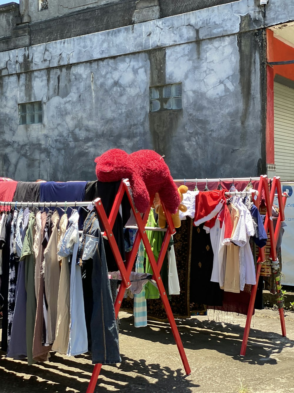 a clothes rack with clothes and a teddy bear on it