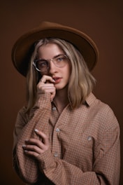 a woman wearing glasses and a hat poses for a picture