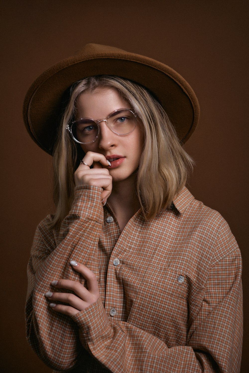 a woman wearing glasses and a hat poses for a picture
